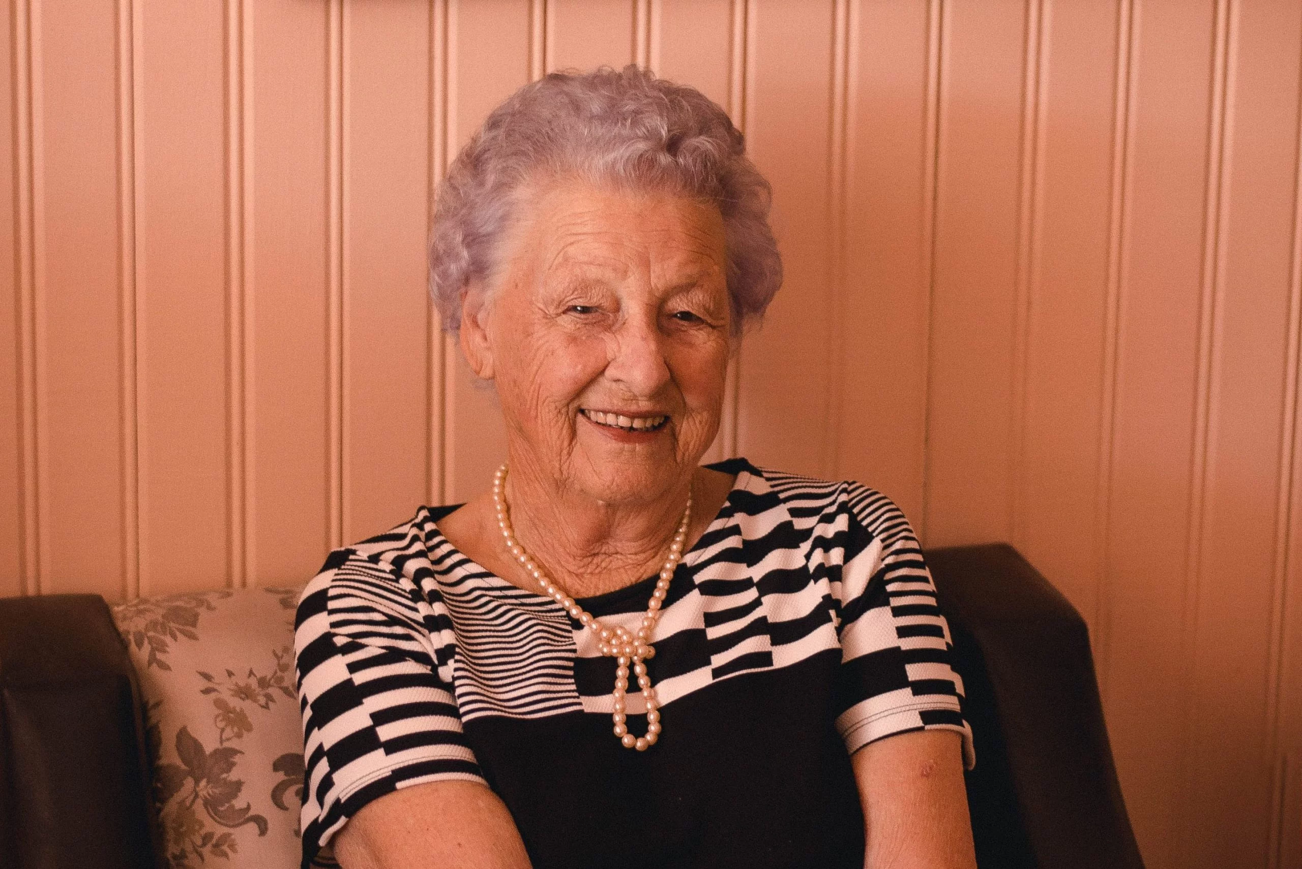 Reverence Planning, LLC 2 smiling woman wearing black and grey dress sitting on sofa 2269717 4 1024x684 1 scaled